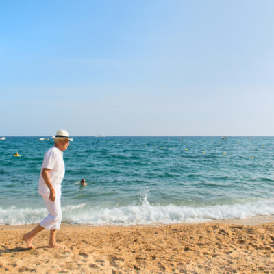 Senior man in white suit walking at the beach
